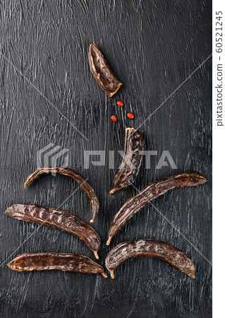 Carob fruit on a black textured background in the 60521245