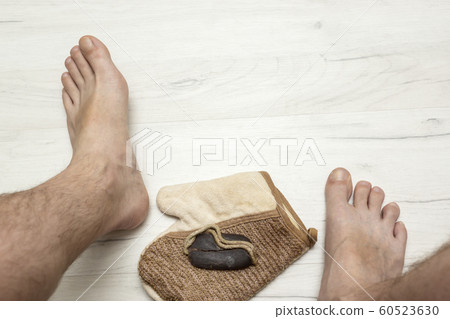 Man's bare feet on and tar soap with and a washcloth on wooden board Man's bare feet on and tar soap with and a washcloth on wooden board 60523630