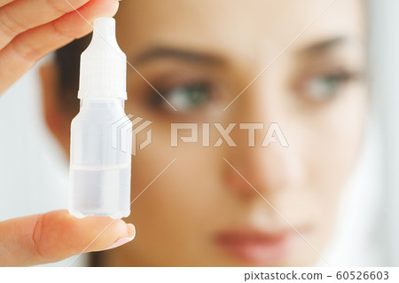 Vision And Medicine Concept. Young Girl Holds Eye Drops In Hands. Portrait of a Beautiful Woman with Contact Lenses. Healthy Look. High Resolution Vision And Medicine Concept. Young Girl Holds Eye Drops In Hands. Portrait of a Beautiful Woman with Contact Lenses. Healthy Look. High Resolution 60526603