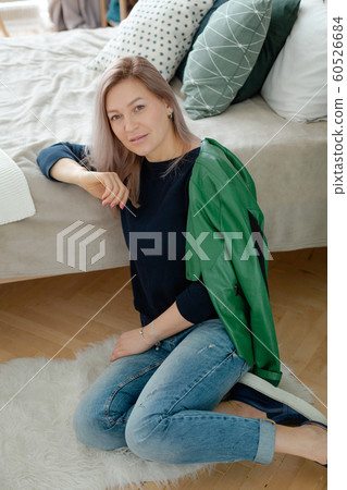 Blonde woman is sitting near the cozy bed Blonde woman is sitting near the cozy bed 60526684