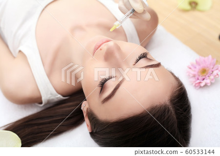 People, cosmetology, plastic surgery and beauty concept - beautiful young woman face and hand in glove with syringe making injection People, cosmetology, plastic surgery and beauty concept - beautiful young woman face and hand in glove with syringe making injection 60533144