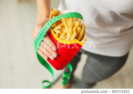 Diet. Woman standing on scales and holding a potato chips. The concept of healthy eating. Healthy Lifestyle. Diet 60533481