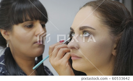 Easy Halloween Makeup. Girl in a beauty salon. Applying a stylistic pattern on the face of the model. The work of a master stylist. Easy Halloween Makeup. Girl in a beauty salon. Applying a stylistic pattern on the face of the model. The work of a master stylist. 60533642