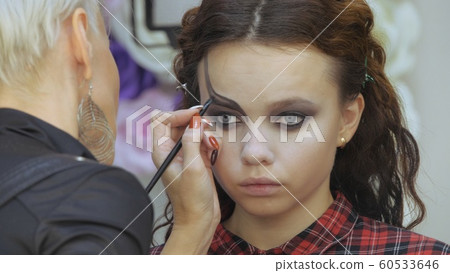 Easy Halloween Makeup. Girl in a beauty salon. Applying a stylistic pattern on the face of the model. The work of a master stylist. 60533646