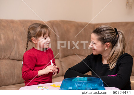 Little caucasian girl has a good time with mom playing the perler beads. Game at home 60534474