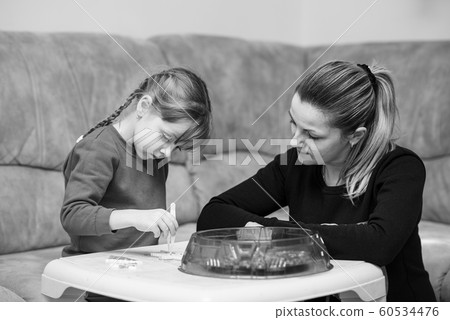 Six year old caucasian girl playing fusible colorful beads. Mom inspires her and watching process 60534476