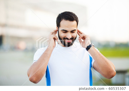 Sport man using headphones for listening music on morning run in park Sport man using headphones for listening music on morning run in park 60535307