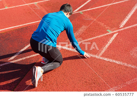 Man athlete on the starting line of a running track at the stadium. Man athlete on the starting line of a running track at the stadium. 60535777
