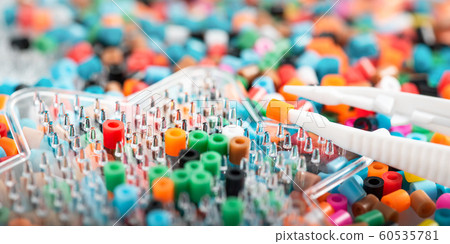 Set of perler beads. Perler pegboard, tweezers and many colorful fusible beads. Toy that develops the imagination of child. Children's toys theme. Wide background with space Set of perler beads. Perler pegboard, tweezers and many colorful fusible beads. Toy that develops the imagination of child. Children's toys theme. Wide background with space 60535781