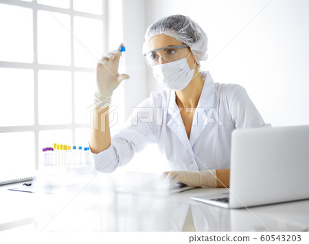 Professional female scientist in protective eyeglasses researching tube with reagents in laboratory. Concepts of medicine and research 60543203