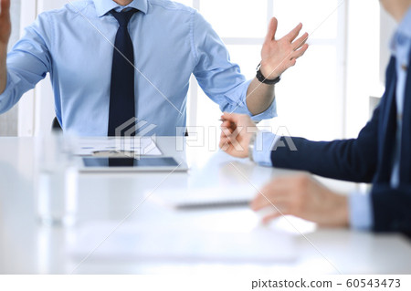 Two unknown businessmen or partners using tablet pc and discussing questions at meeting in modern office, close-up of hands. Group of managers at negotiation or brainstorm. Teamwork, partnership and 60543473