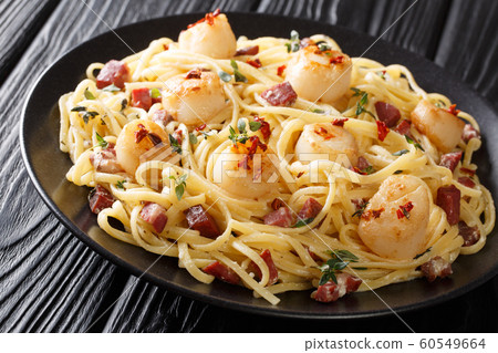 Serving of spaghetti with scallops and bacon in a 60549664