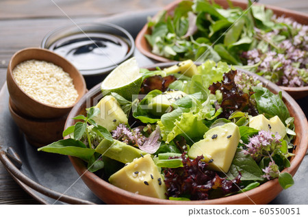 Clay dish with salad of avocado, green and violet 60550051