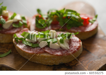 Bruschetta with mozzarella, cherry tomatoes and salame on olive board 60550275