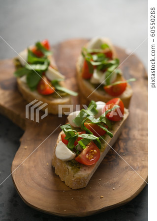 Bruschetta with mozzarella, cherry tomatoes and pesto on olive board 60550288