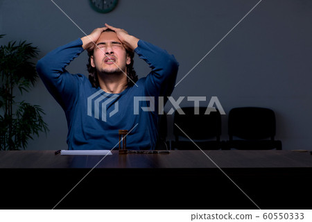 Young convict man sitting in dark room 60550333
