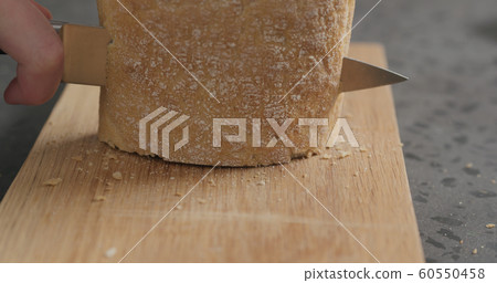 man slicing ciabatta with bread knife on oak board man slicing ciabatta with bread knife on oak board 60550458