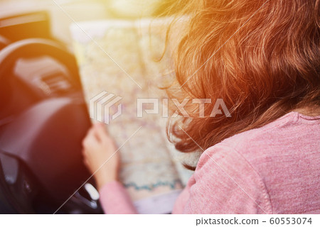 Woman looking at the navigation map while driving Woman looking at the navigation map while driving 60553074