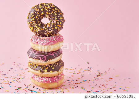 Stack of colorful donuts decorated on a pink Stack of colorful donuts decorated on a pink 60553083