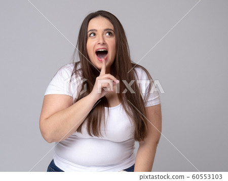 Girl holds finger at mouth urging to keep silence 60553103