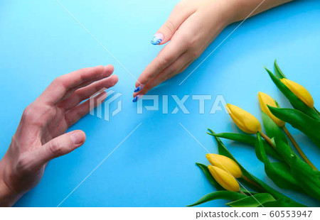 Holding hands on blue background with tulips, topdown view, holidays concept Holding hands on blue background with tulips, topdown view, holidays concept 60553947
