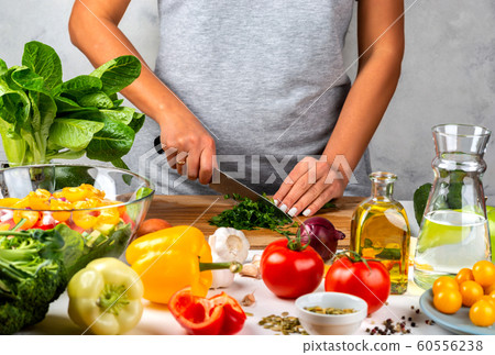 Woman cuts greens and cooking salad in the kitchen. Healthy diet concept. 60556238