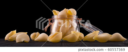 Jar of conchiglie pasta shell on wooden table isolated on black background 60557369