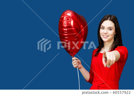 Girl in a red dress shows a finger at the camera. Girl in a red dress shows a finger at the camera. 60557922