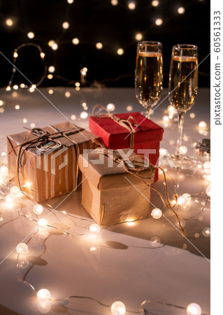 Three packed giftboxes, two flutes of champagne on table decorated with garlands 60561333