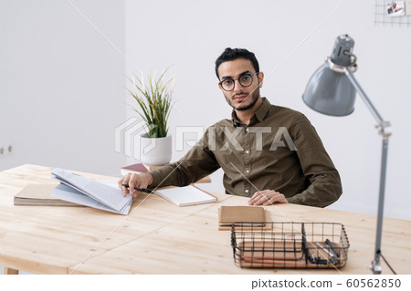 Young serious businessman in casualwear and eyeglasses planning work Young serious businessman in casualwear and eyeglasses planning work 60562850