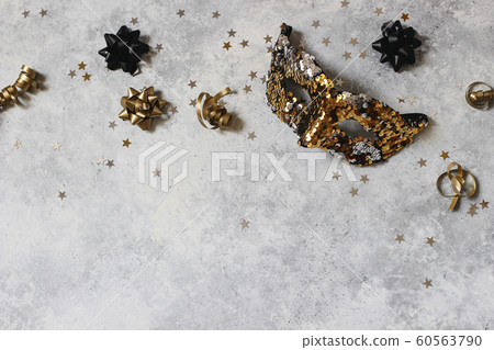 New Year festive composition, web banner with carnival mask, black and gold confetti stars. Party decoration, celebration concept. Flat lay, top view. Grunge concrete background. Empty copy space. New Year festive composition, web banner with carnival mask, black and gold confetti stars. Party decoration, celebration concept. Flat lay, top view. Grunge concrete background. Empty copy space. 60563790
