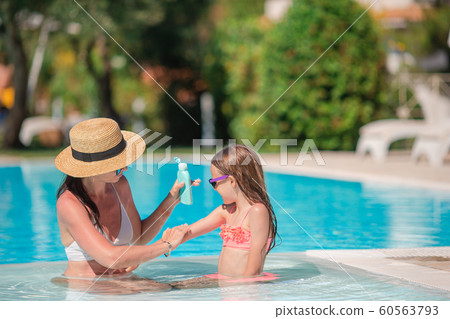 Young mother applying sun cream to daughter nose on the beach. Young mother applying sun cream to daughter nose on the beach. 60563793