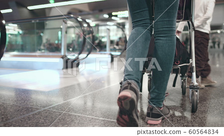 woman with luggage cart walk at airport terminal woman with luggage cart walk at airport terminal 60564834