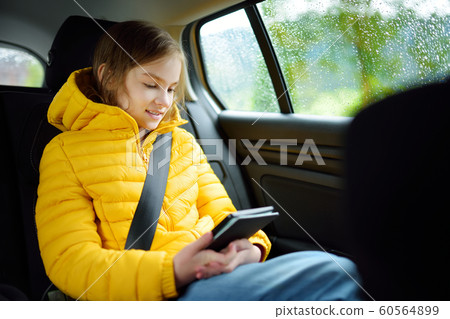 Adorable girl sitting in a car and reading her 60564899