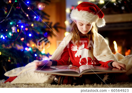 Happy little girl reading a story book by a 60564923