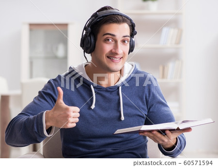 Young man reading book and listening to audio book 60571594