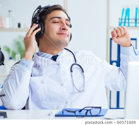 Happy excited doctor listening to music during lunch break in ho 60571889