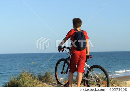 a boy with a Bicycle on a hill looks at the sea a boy with a Bicycle on a hill looks at the sea 60575698