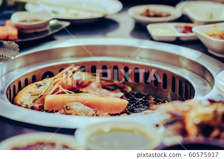 People grilling meat on a smokeless barbecue grill in a restaurant. 60575917