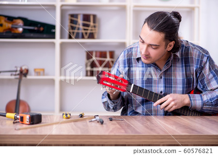 Young handsome repairman repairing guitar Young handsome repairman repairing guitar 60576821