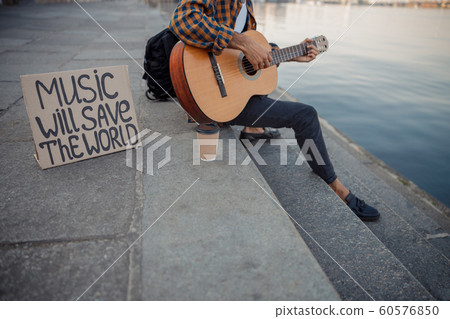 Musician playing guitar while resting near river 60576850