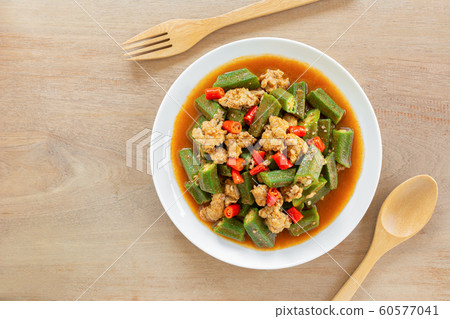top view of stir fried okra with red curry paste and pork in a ceramic dish on wooden table. top view of stir fried okra with red curry paste and pork in a ceramic dish on wooden table. 60577041