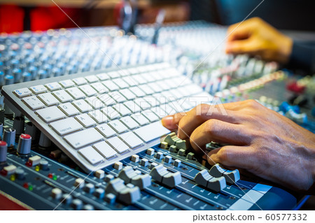 male producer, sound engineer hands pressing computer keyboard on audio mixing concole in recording, broadcasting studio 60577332