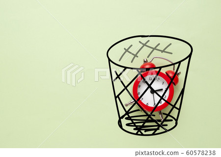 Red alarm clock in a waste paper bin 60578238