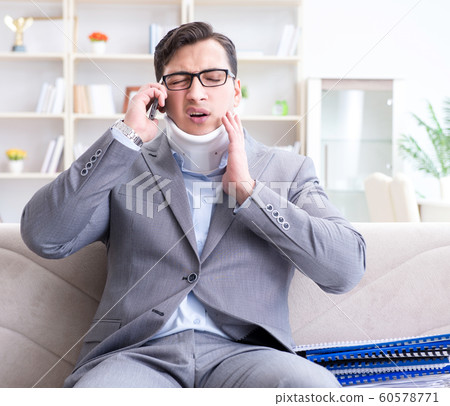 Man in neck brace cervical collar working from home teleworking 60578771