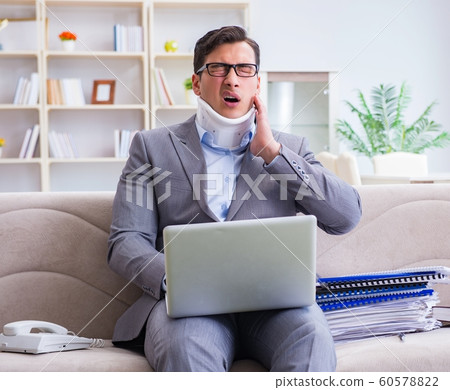 Man in neck brace cervical collar working from home teleworking Man in neck brace cervical collar working from home teleworking 60578822