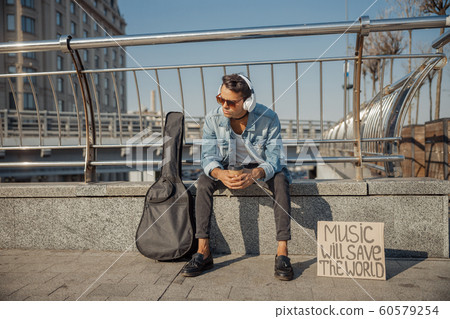 Stylish musician is resting on the street Stylish musician is resting on the street 60579254