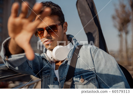 Stylish young guitarist looking at camera outdoors 60579313