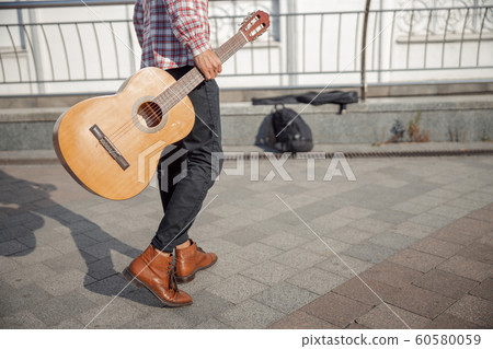 Young guy with guitar walking along the street Young guy with guitar walking along the street 60580059