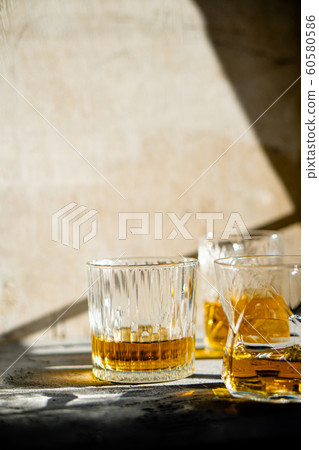 Whiskey in glasses on table in bright sunlight, yellow drink Whiskey in glasses on table in bright sunlight, yellow drink 60580586